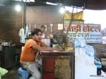 An Indian man waits for customers at the counter of his eatery- Baitadi Hotel- in Banbasa, India that is named after a district of Nepal in far west that borders India. The sign board assures good food in Nepali language. Banbasa, a border town, is the starting point for many buses that reach Delhi in about 9 hours.